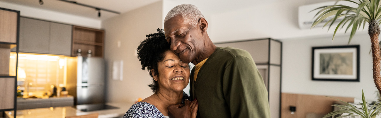 A couple standing in their home find the freedom of forgiveness and embrace each other with smiles