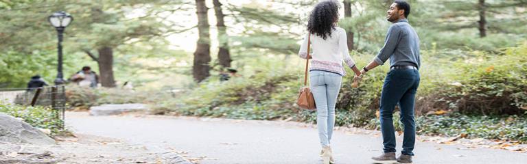 man and woman walking hand-in-hand down a country road
