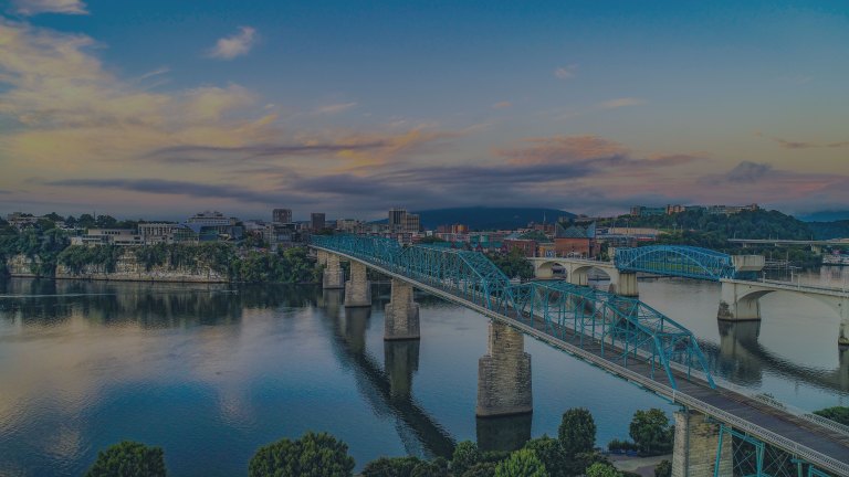 A riverside view directly in front of the downtown Chattanooga skyline, showing off the Tennessee River and the Walnut Street Bridge, an historic pedestrian truss bridge in Chattanooga, Tennessee, a location of FamilyLife's Weekend to Remember® marriage retreat event.