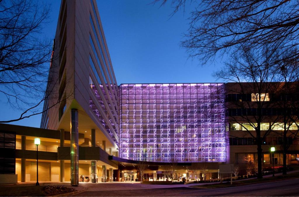 A streetside view of the Hyatt Regency Greenville, a modern and unusual building with an elevated triangle-shaped section on one end that is set upon pillars above the lower floors and found in the city of Greenville, South Carolina, a location of FamilyLife's Weekend to Remember® marriage retreat event.