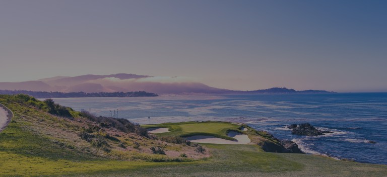 A morning ocean view in pastel colors, with an eye toward the horizon of low-lying, cloud-covered hills, and overlooking the beautifully maintained greens of a world-class golf course hole sitting on the rocky edge coastline of Monterey, California, a location of FamilyLife's Weekend to Remember® marriage retreat event.