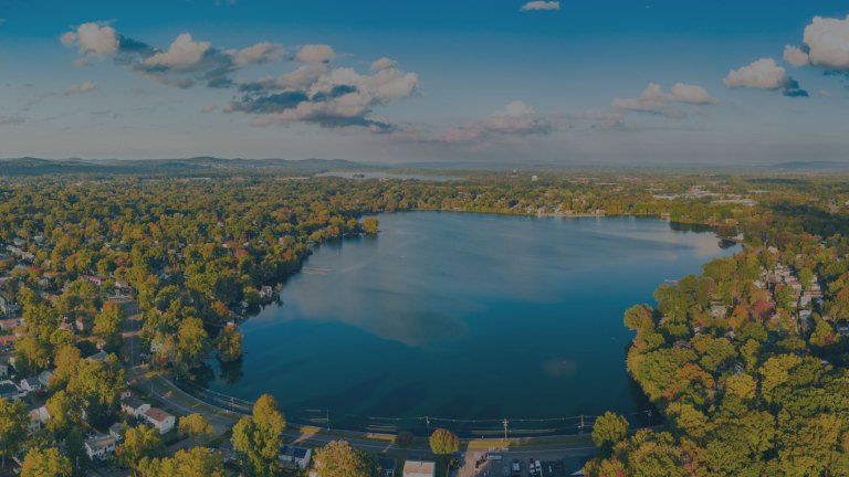 An aerial view over a large lake surrounded by dense forest and residential areas in Parsippany, New Jersey, a location of FamilyLife's Weekend to Remember® marriage retreat event.
