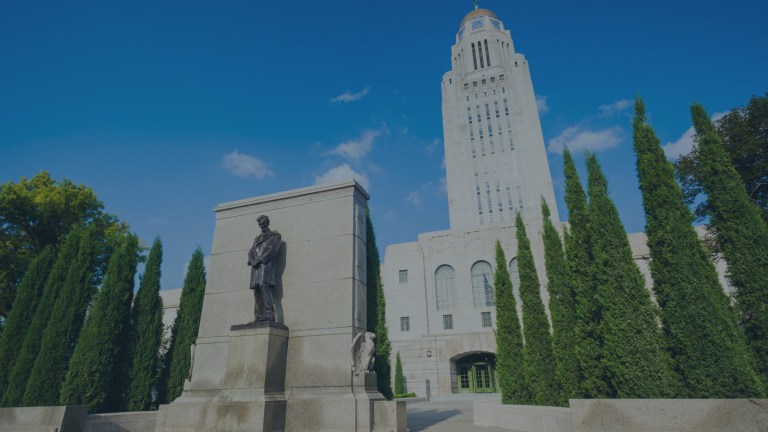 A street view looking up at the Nebraska State Capitol building and monument with a bronze statue of Abraham Lincoln in Lincoln, Nebraska, a location of FamilyLife's Weekend to Remember® marriage retreat event.