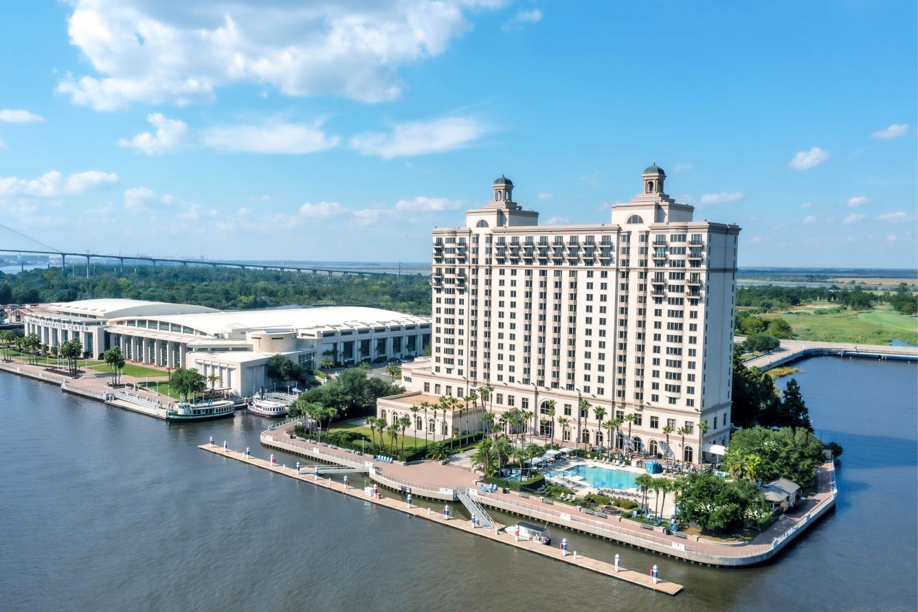 A background of blue skies with a few puffy clouds showcases this beautiful aerial view of The Westin Savannah Harbor Golf Resort & Spa, situated near the confluence of the Savannah River and the Back River, both of which wind around the resort and its golf course in Savannah, Georgia, a location of FamilyLife's Weekend to Remember® marriage retreat event