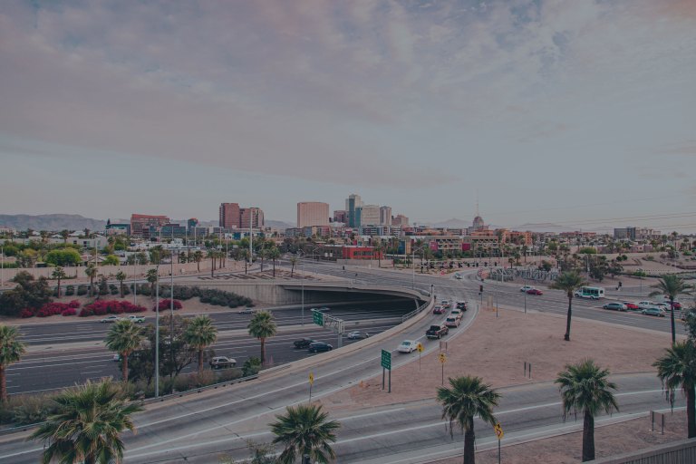 This wide view overlooks a highway interchange leading to streets lined with desert colored brick pathways and tall palm trees, and then into the desert colored downtown buildings of Scottsdale, Arizona, a location of FamilyLife's Weekend to Remember® marriage retreat event.